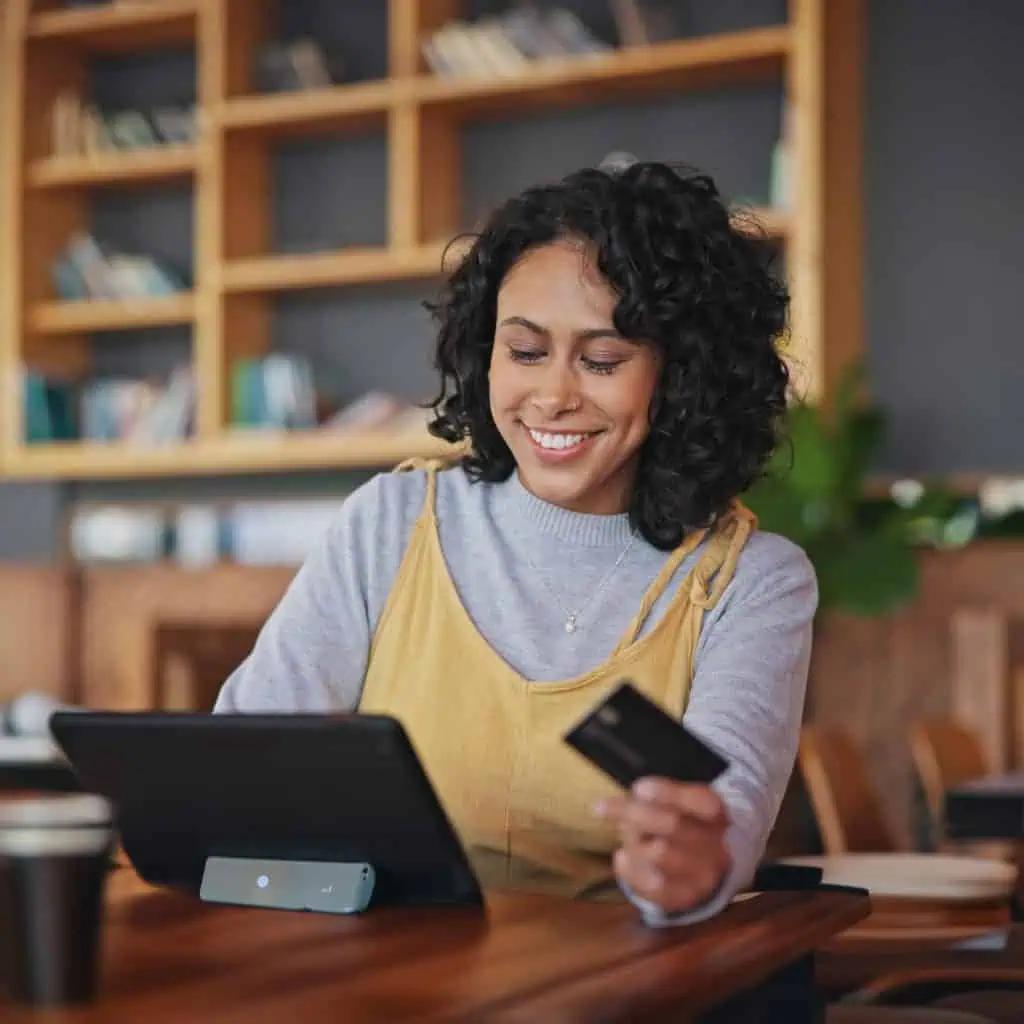 woman looking at tablet holding card